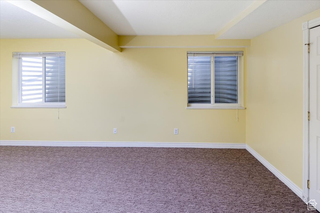 Spare room featuring beam ceiling and carpet flooring