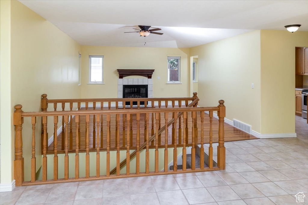 Staircase with a tile fireplace, tile patterned flooring, and ceiling fan