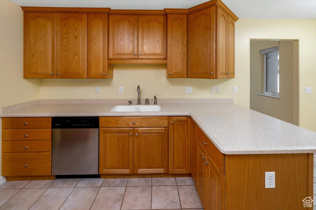 Kitchen with light tile patterned floors, dishwasher, sink, and kitchen peninsula