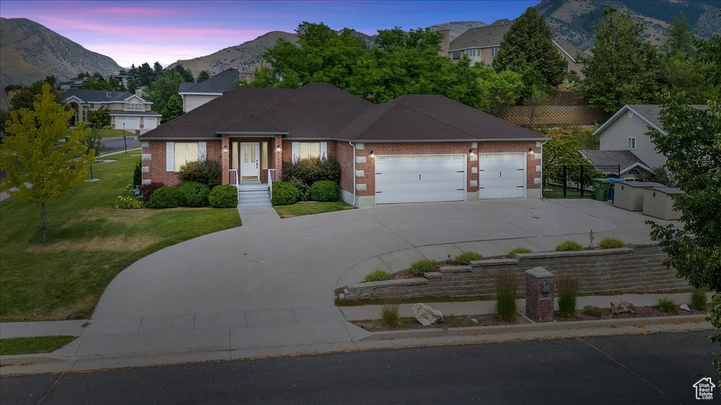 View of front facade featuring a garage, a lawn, and a mountain view