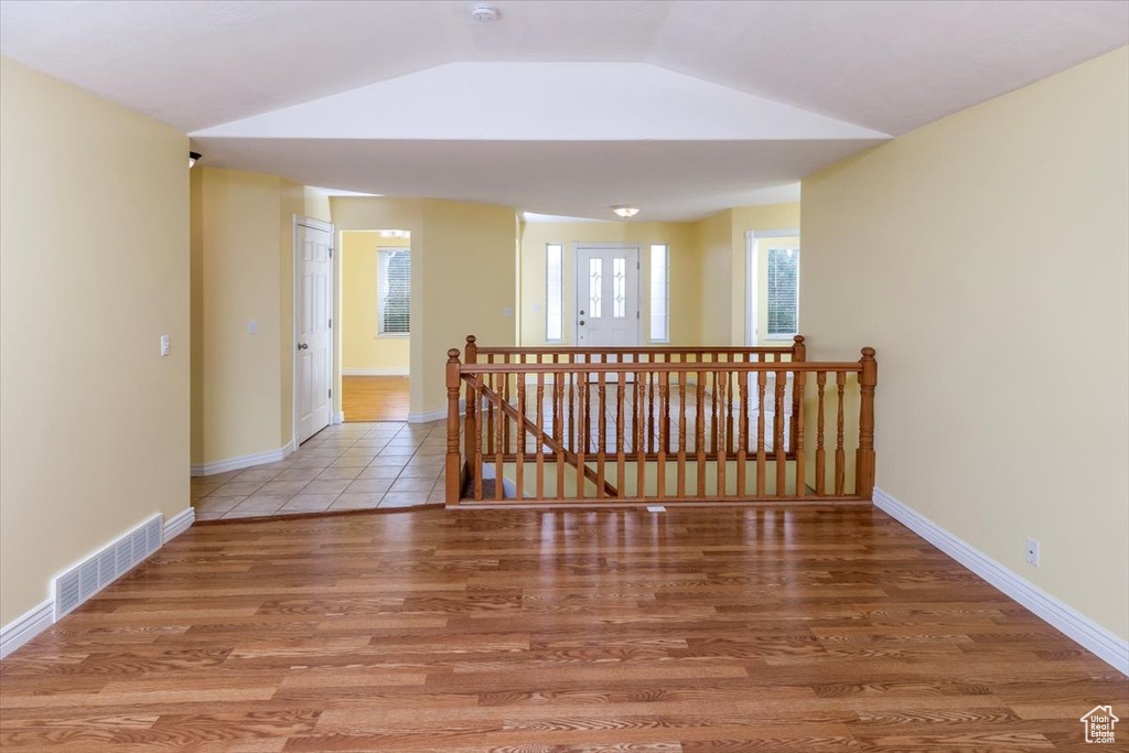 Hall with vaulted ceiling, hardwood / wood-style flooring, and a healthy amount of sunlight