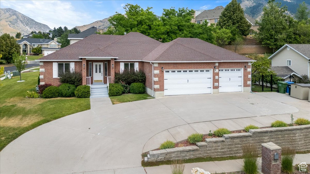 Single story home featuring a mountain view, a garage, and a front lawn