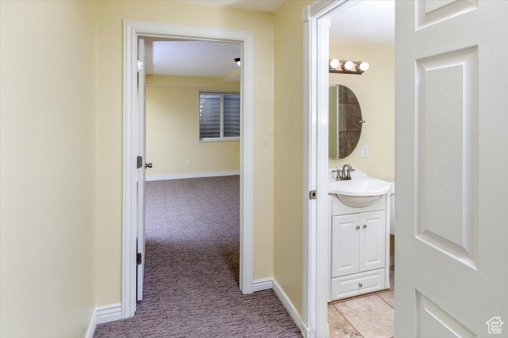 Corridor featuring sink and light carpet