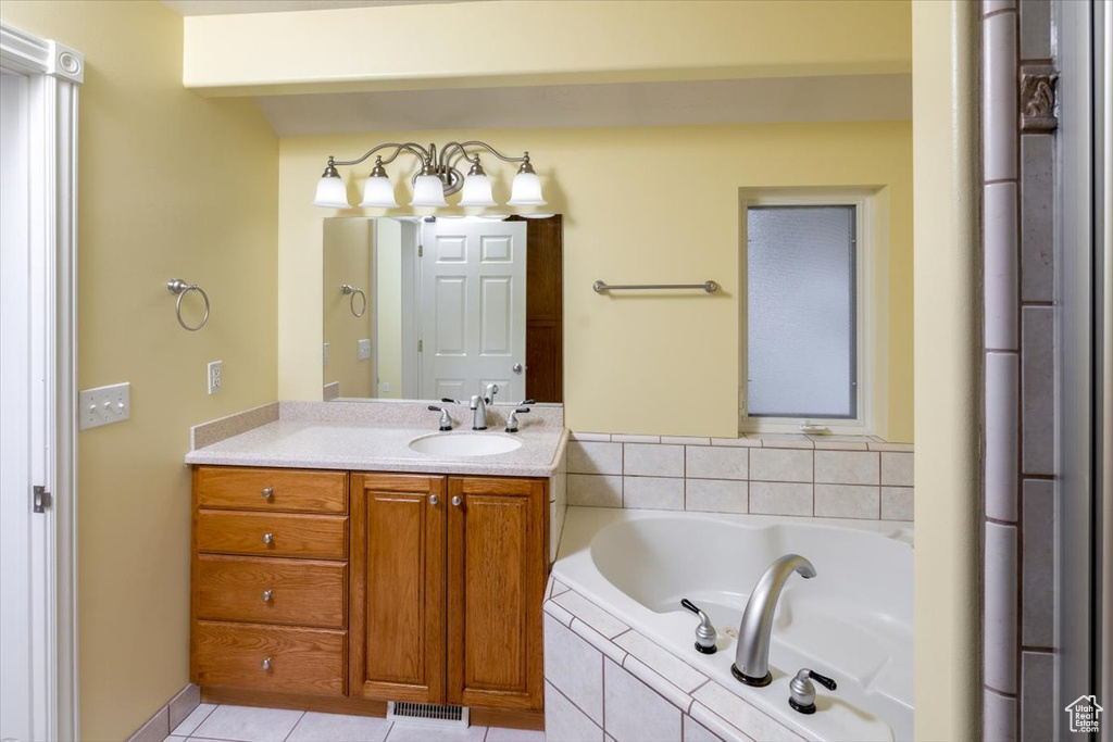 Bathroom with a relaxing tiled tub, tile patterned flooring, and vanity