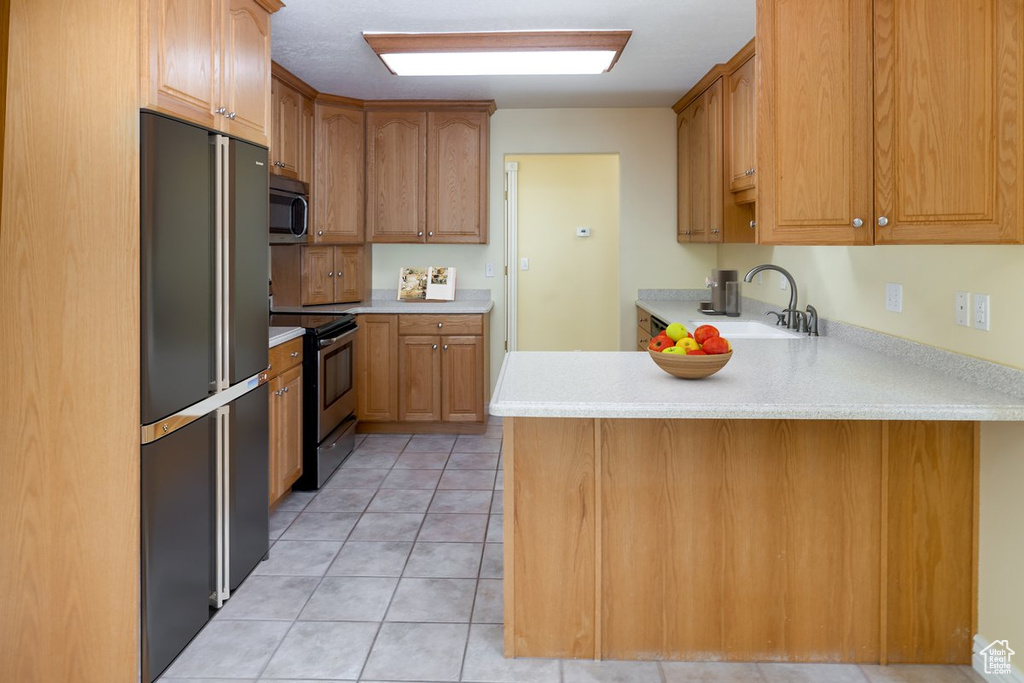 Kitchen featuring sink, kitchen peninsula, stainless steel appliances, and light tile patterned floors