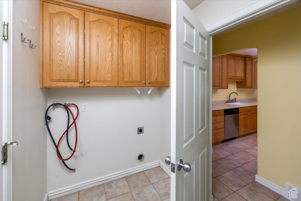 Washroom featuring sink, hookup for an electric dryer, hookup for a washing machine, and light tile patterned floors