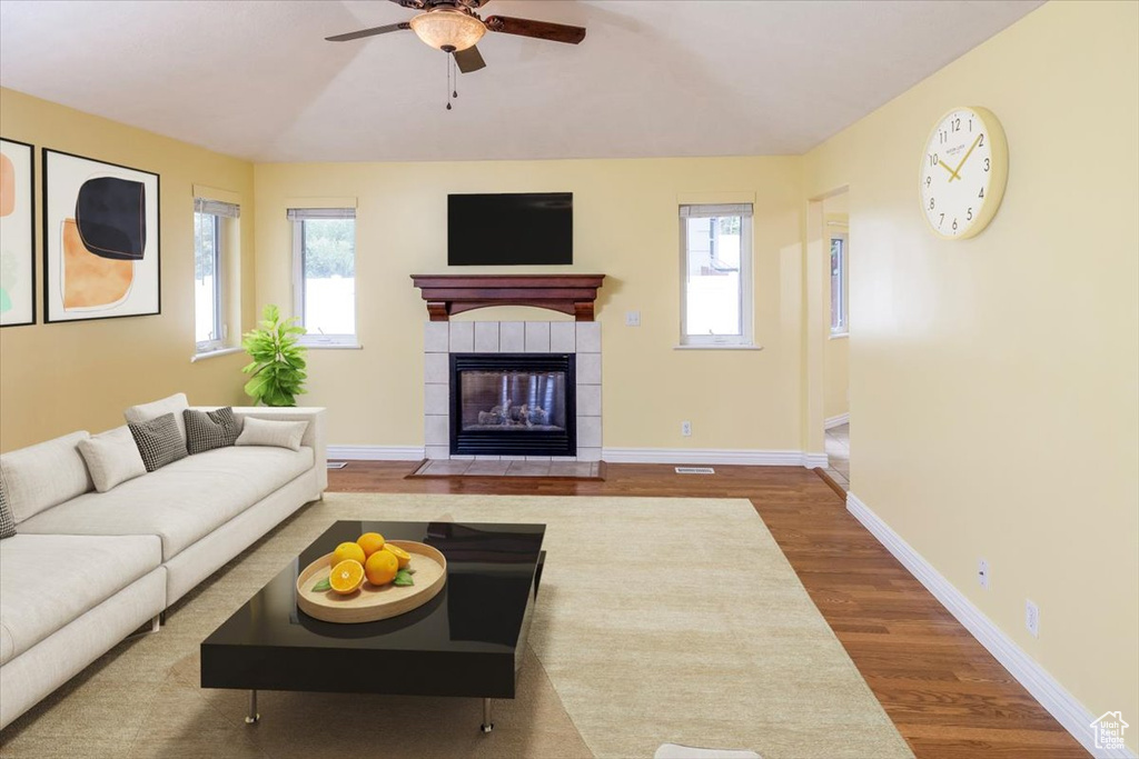 Living room featuring a fireplace, hardwood / wood-style floors, and ceiling fan