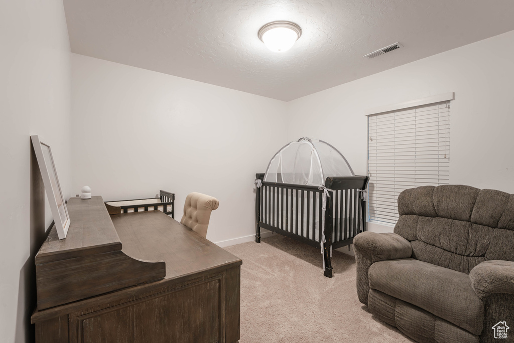 Bedroom featuring light carpet and a nursery area