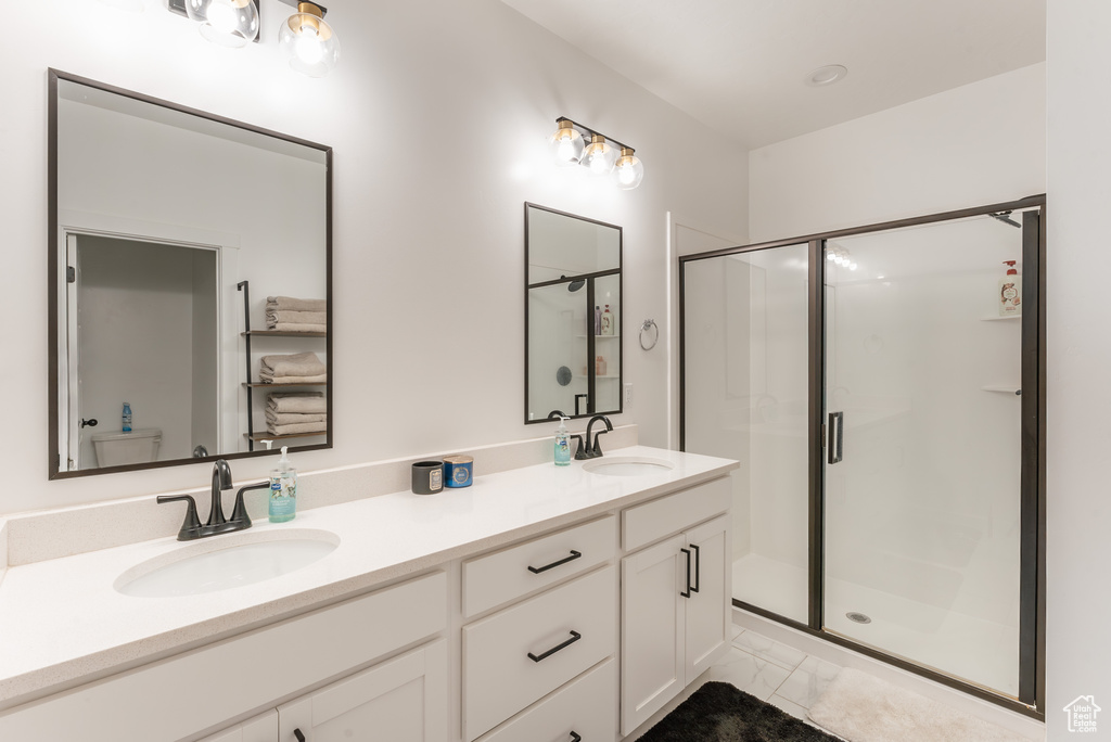 Bathroom with tile patterned floors, an enclosed shower, and double vanity