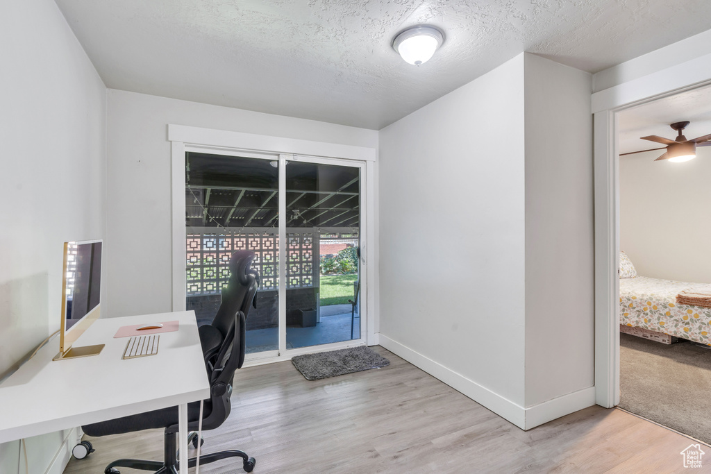 Office area with a textured ceiling, ceiling fan, and light colored carpet