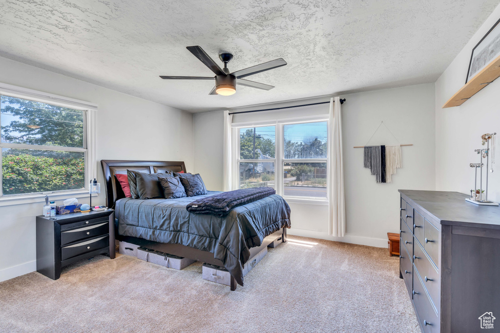 Bedroom featuring a textured ceiling, ceiling fan, and light colored carpet