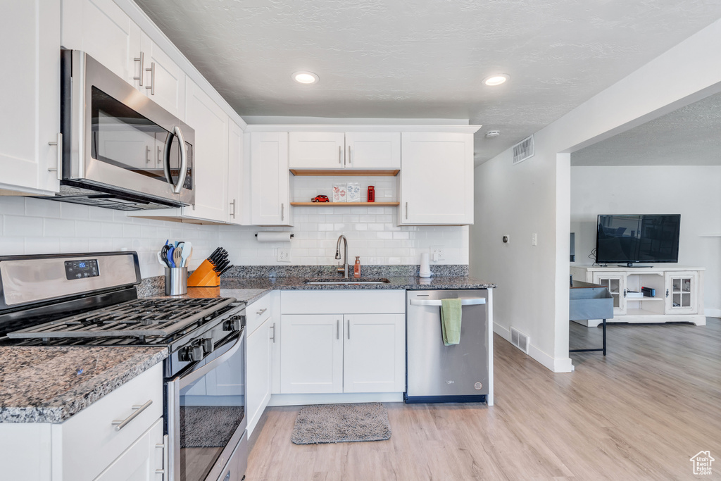 Kitchen featuring light hardwood / wood-style floors, sink, decorative backsplash, and stainless steel appliances