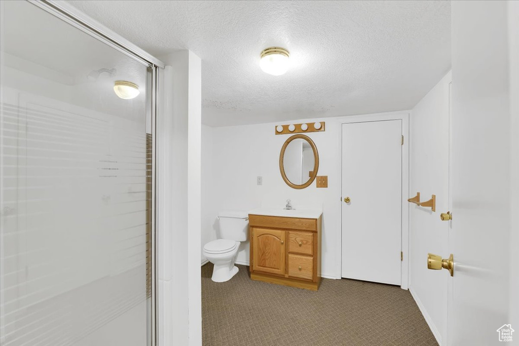 Bathroom with vanity, an enclosed shower, a textured ceiling, and toilet