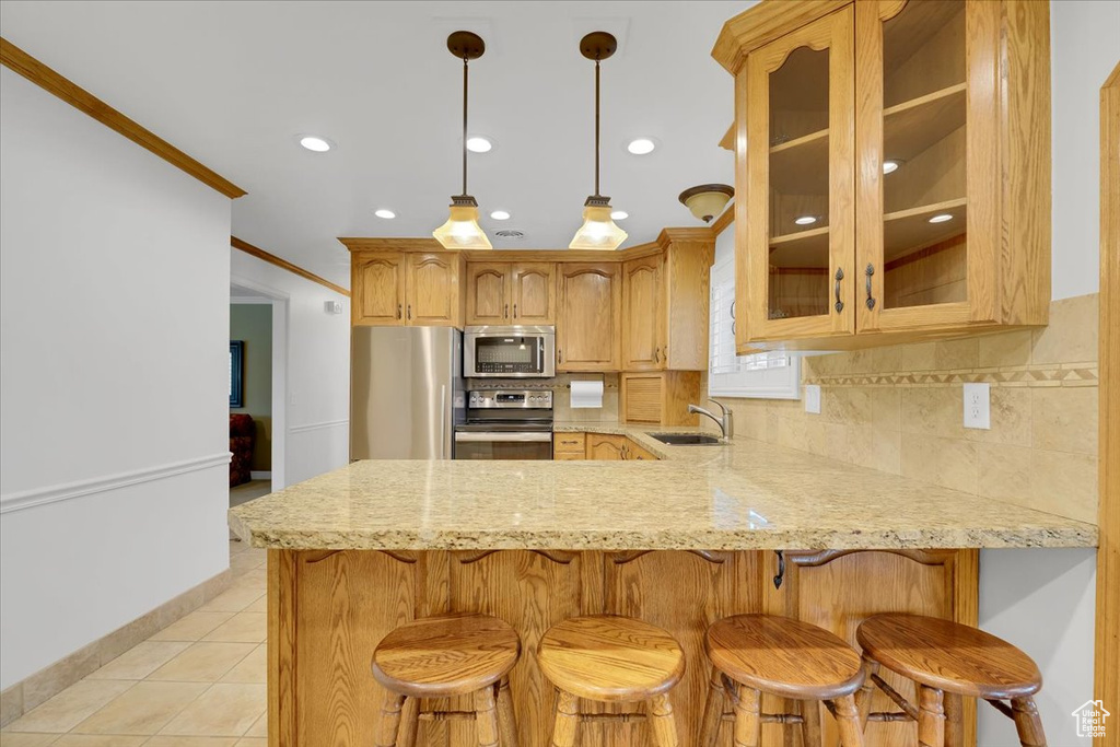 Kitchen featuring kitchen peninsula, backsplash, appliances with stainless steel finishes, sink, and ornamental molding