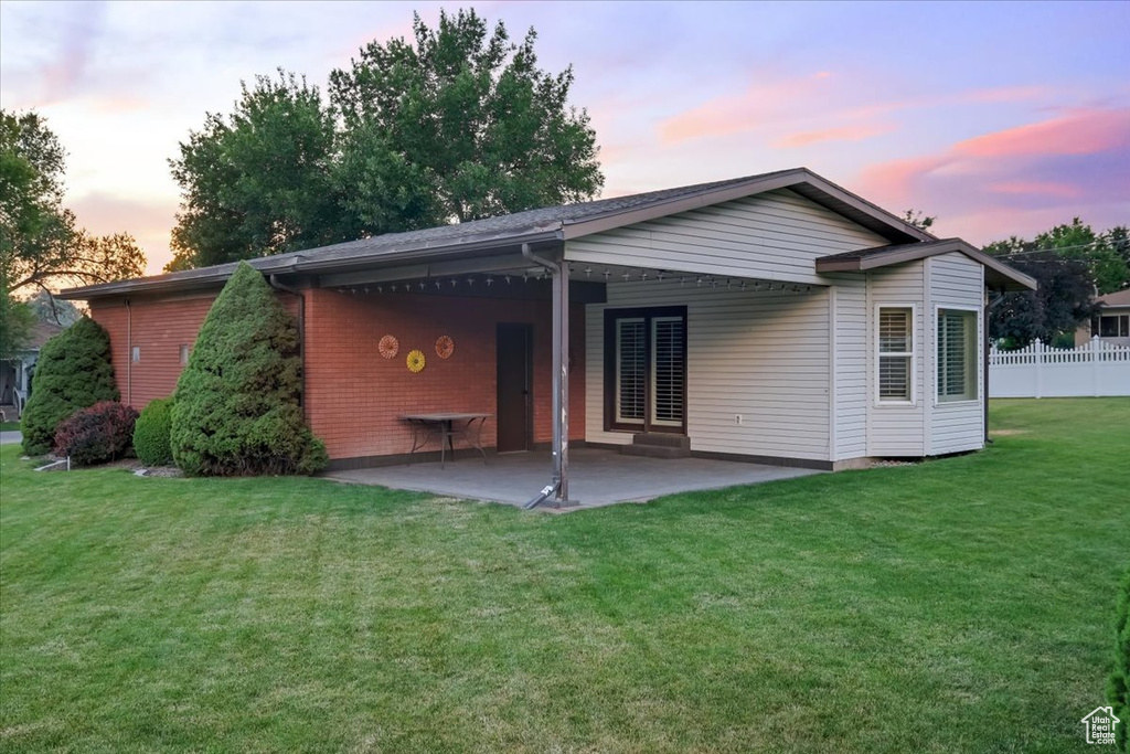 Back house at dusk with a patio area and a yard