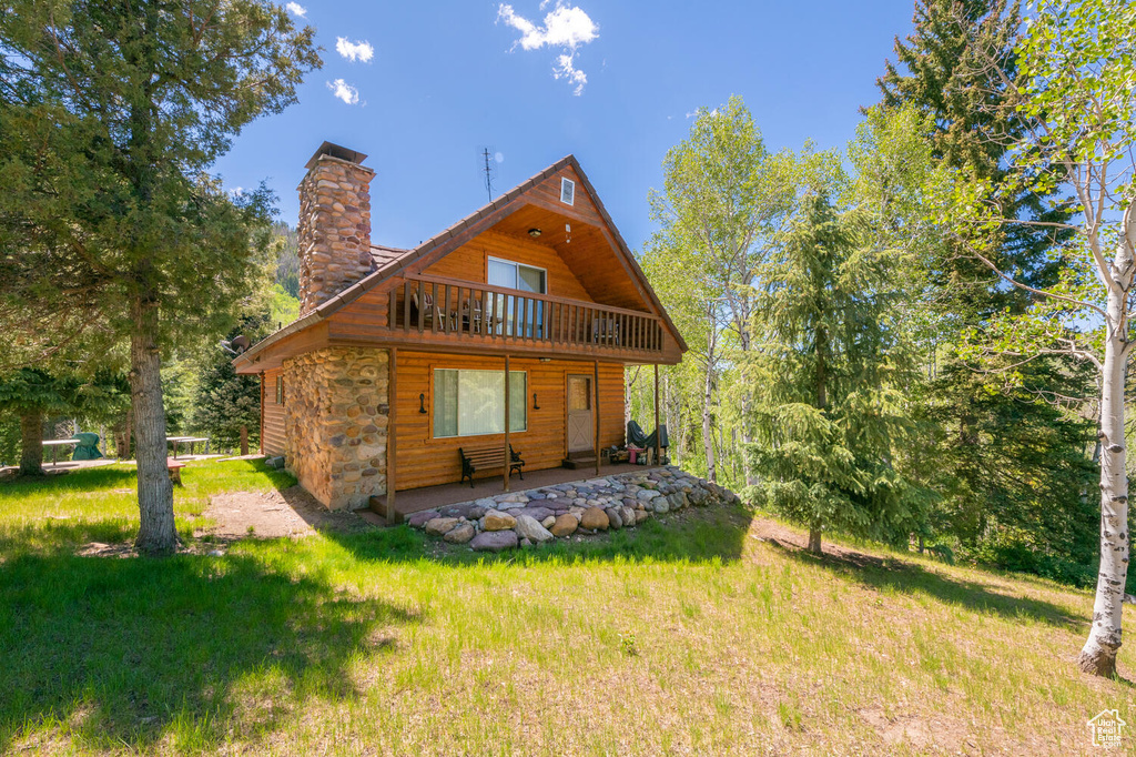 Back of property featuring a balcony and a lawn