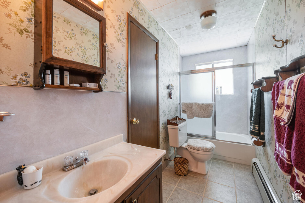 Full bathroom with tile patterned flooring, shower / bath combination with glass door, toilet, vanity, and a baseboard radiator