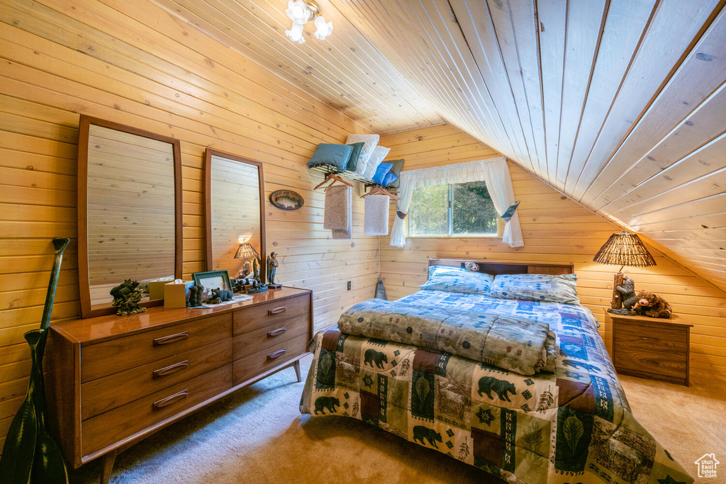 Carpeted bedroom with lofted ceiling, wooden walls, and wood ceiling