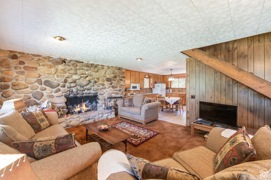 Living room featuring wood walls, carpet flooring, and a fireplace