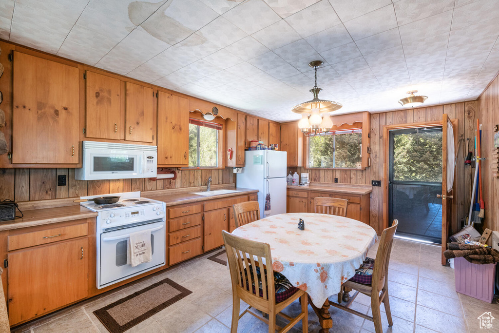 Kitchen with white appliances, a chandelier, light tile patterned floors, decorative light fixtures, and sink