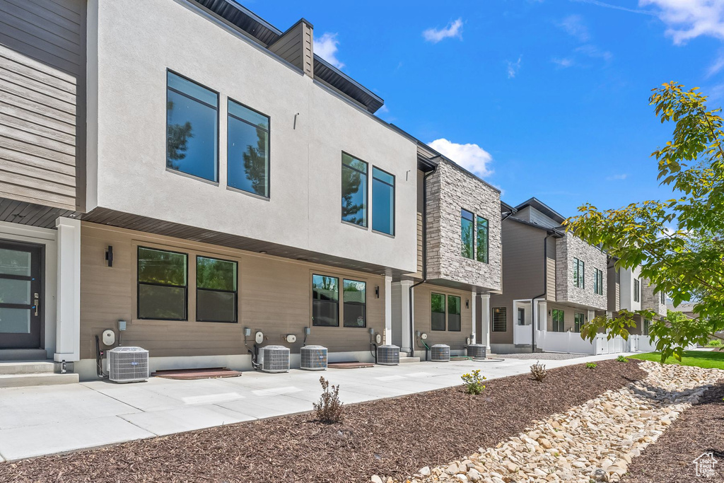 Back of property with cooling unit and a patio area