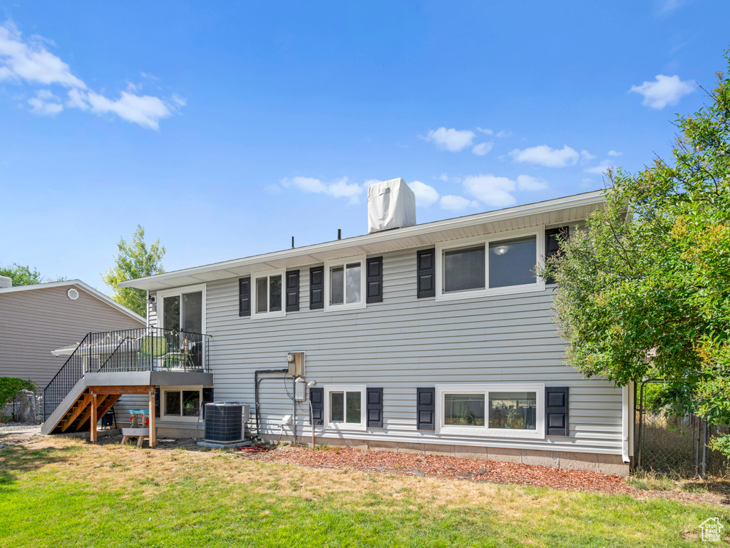 Rear view of property featuring a deck, central air condition unit, and a yard