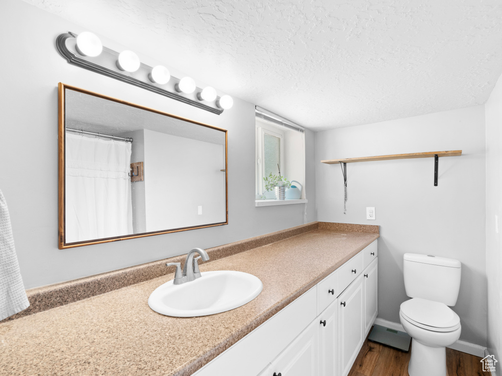 Bathroom featuring vanity, a textured ceiling, toilet, and hardwood / wood-style floors