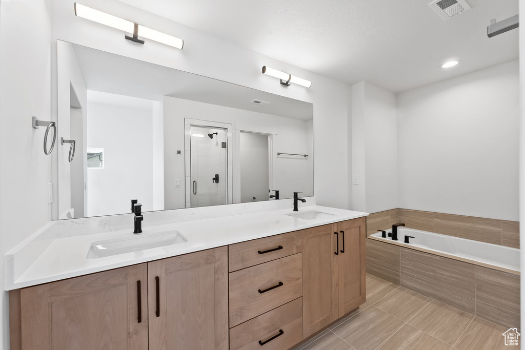 Bathroom with shower with separate bathtub, double sink vanity, and tile patterned flooring