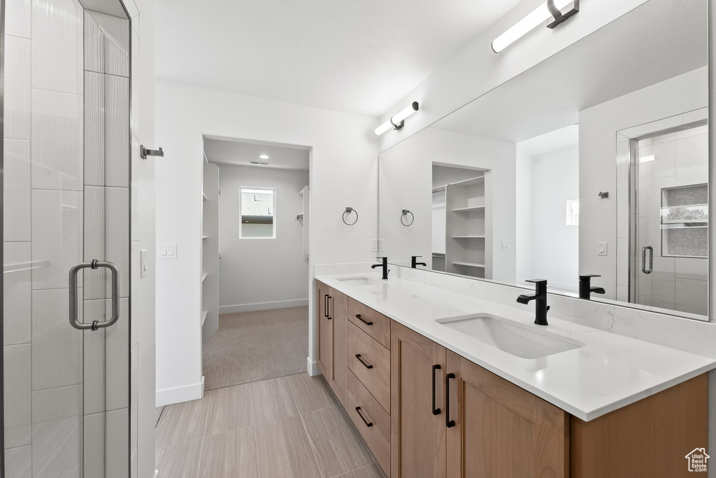 Bathroom with tile patterned flooring, a shower with shower door, and dual bowl vanity