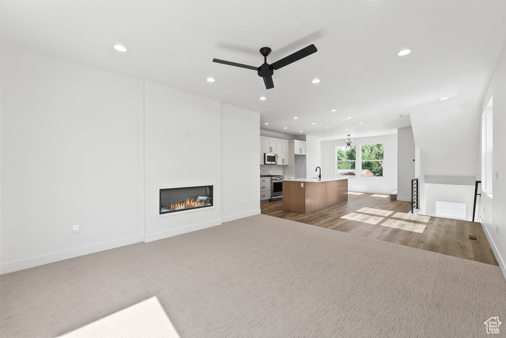 Unfurnished living room featuring sink, light hardwood / wood-style flooring, and ceiling fan