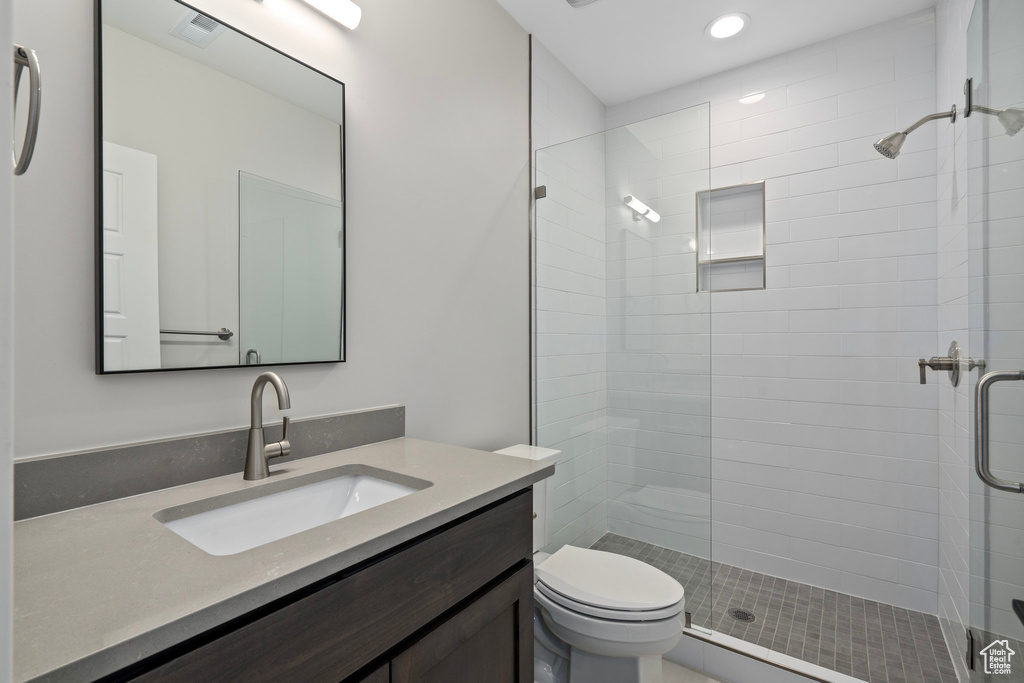 Bathroom featuring vanity, an enclosed shower, and toilet