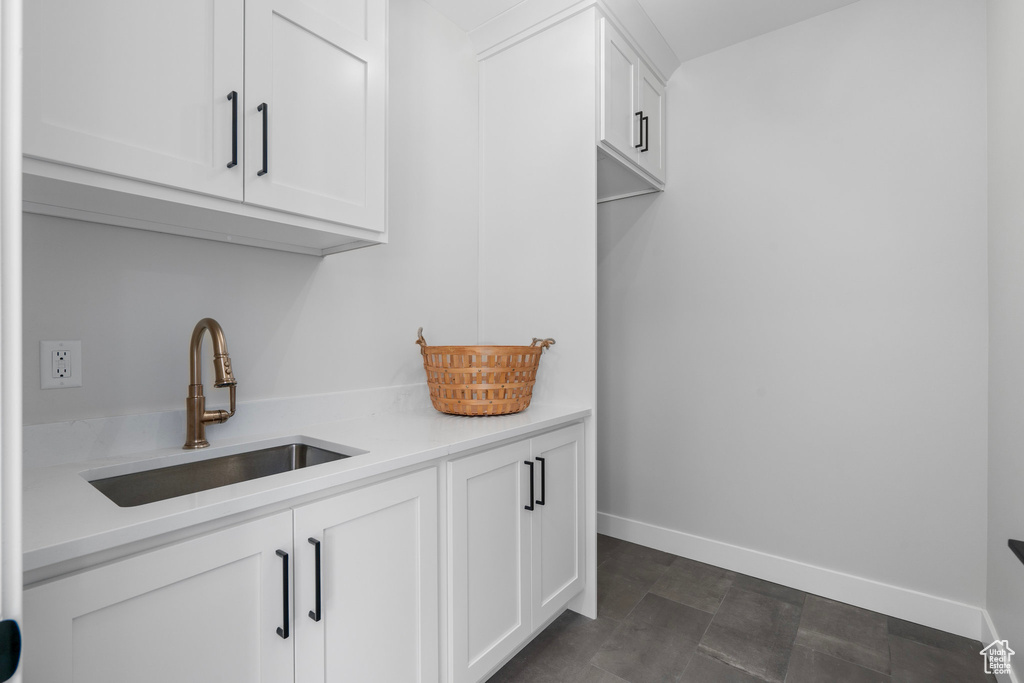 Interior space featuring white cabinets, dark tile patterned floors, and sink