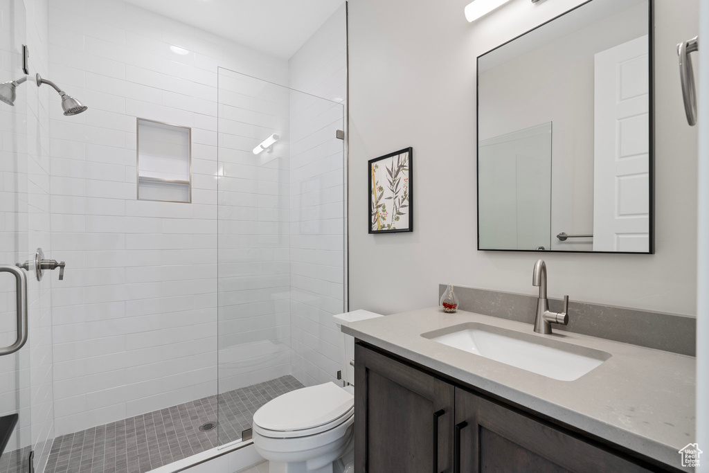 Bathroom with a shower with door, toilet, and vanity