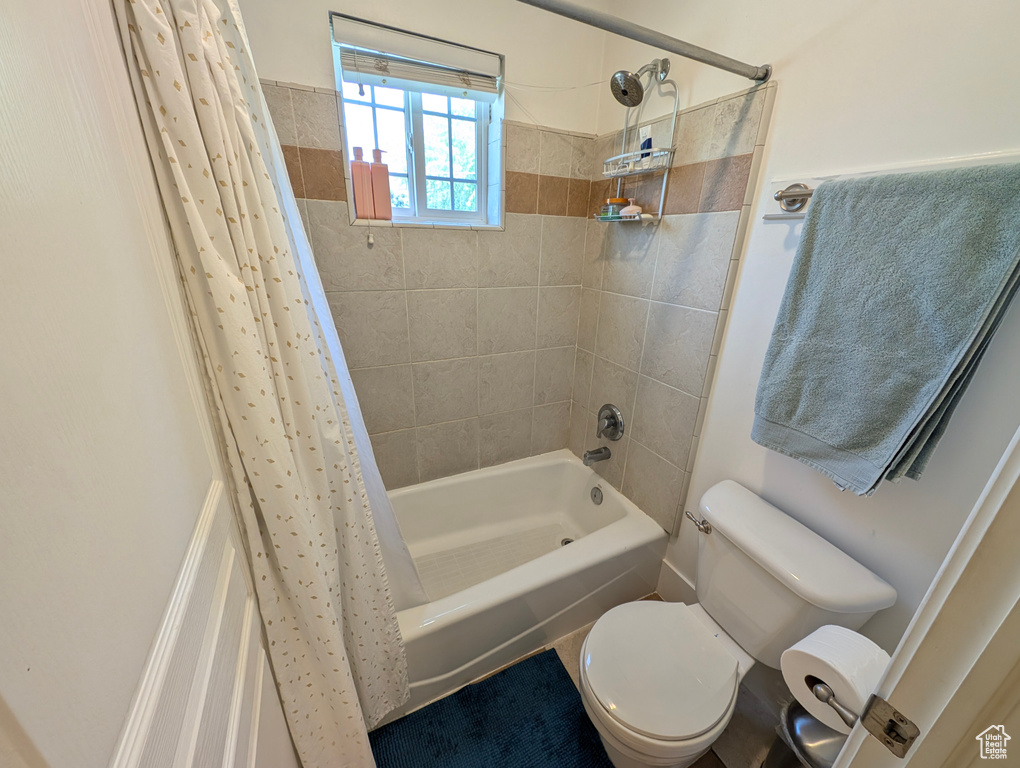 Bathroom with toilet and shower / bathtub combination with curtain