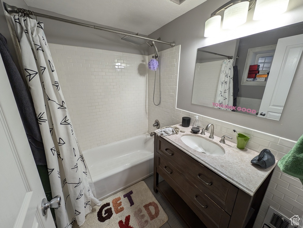 Bathroom featuring vanity, tasteful backsplash, shower / bath combo, and tile walls