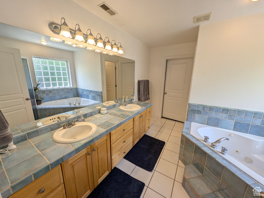 Bathroom featuring tile patterned floors, tiled tub, and double sink vanity