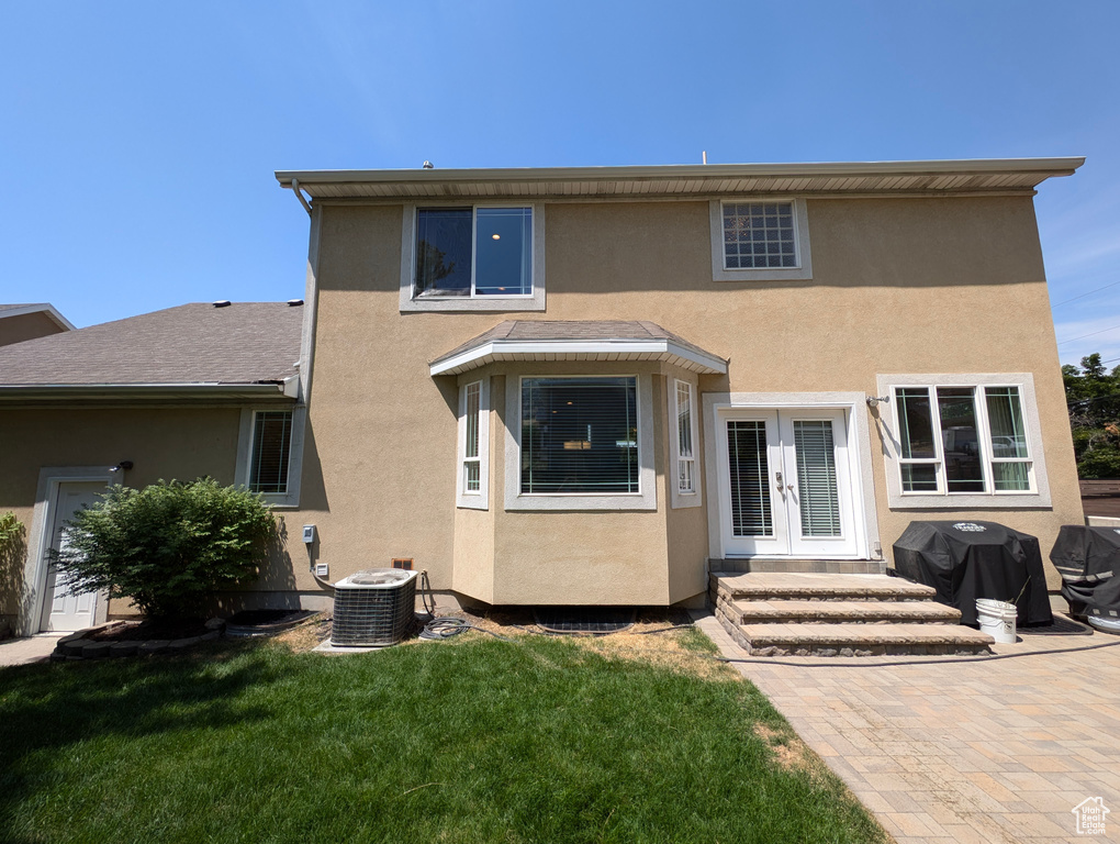 Back of property featuring a yard, a patio, french doors, and cooling unit