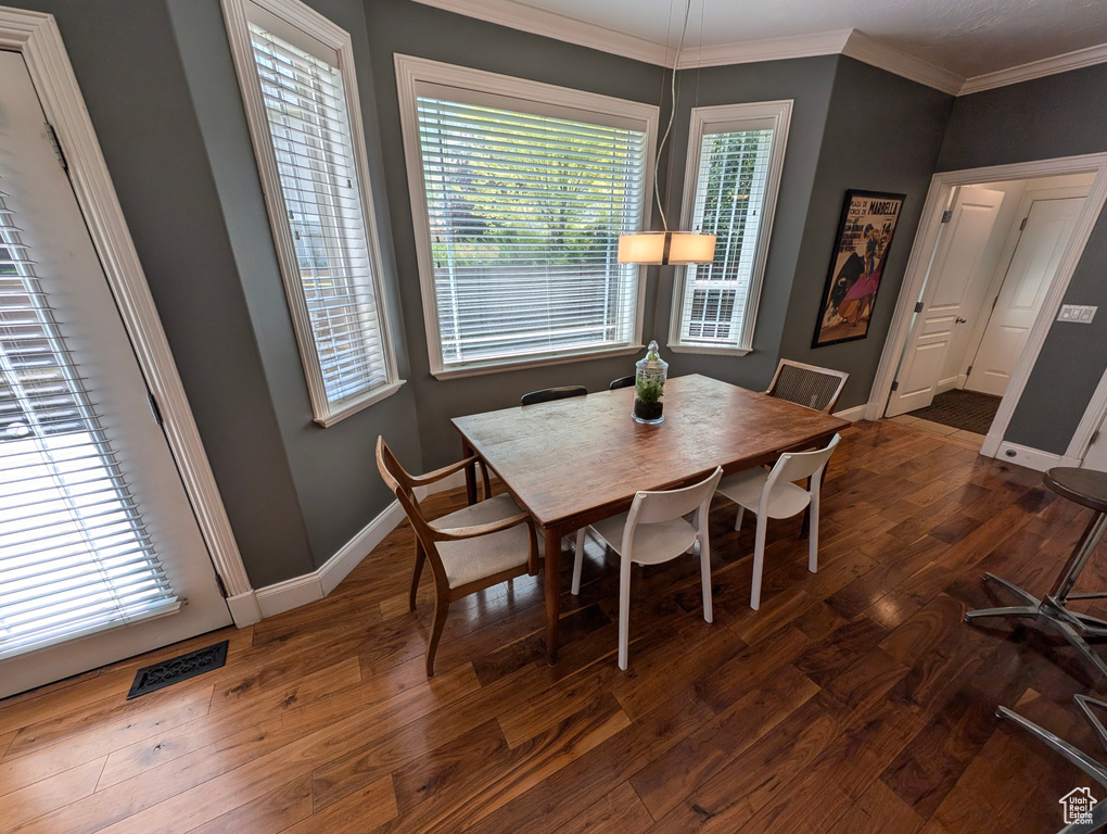 Dining room with a wealth of natural light, dark hardwood / wood-style floors, and ornamental molding