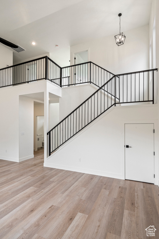 Stairway featuring an inviting chandelier, a high ceiling, and light hardwood / wood-style floors