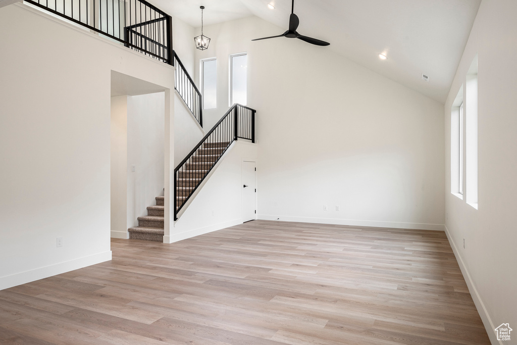 Unfurnished living room featuring hardwood / wood-style flooring, high vaulted ceiling, and ceiling fan