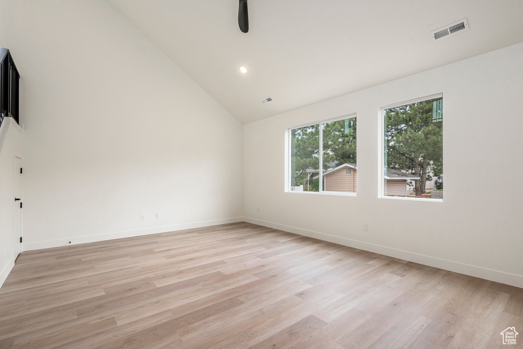 Empty room with light hardwood / wood-style flooring and high vaulted ceiling