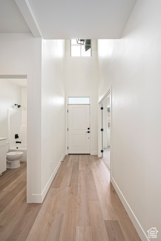 Hallway with a towering ceiling and light hardwood / wood-style flooring