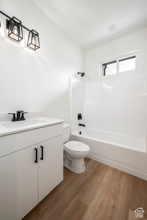 Full bathroom with toilet, bathtub / shower combination, hardwood / wood-style floors, and vanity