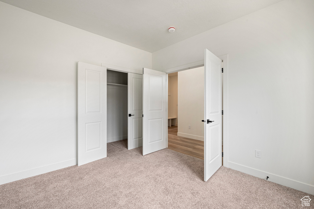 Unfurnished bedroom with a closet and light colored carpet