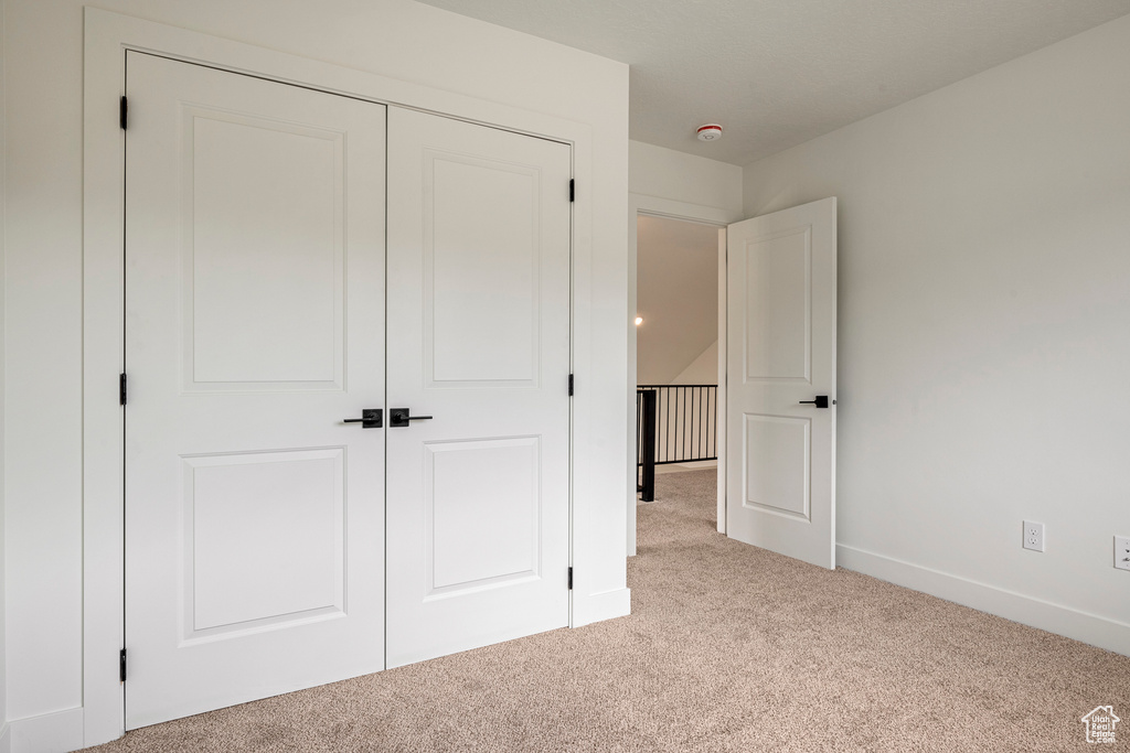 Unfurnished bedroom featuring light colored carpet and a closet