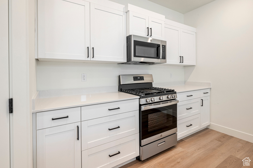 Kitchen featuring white cabinetry, stainless steel appliances, and light wood-type flooring