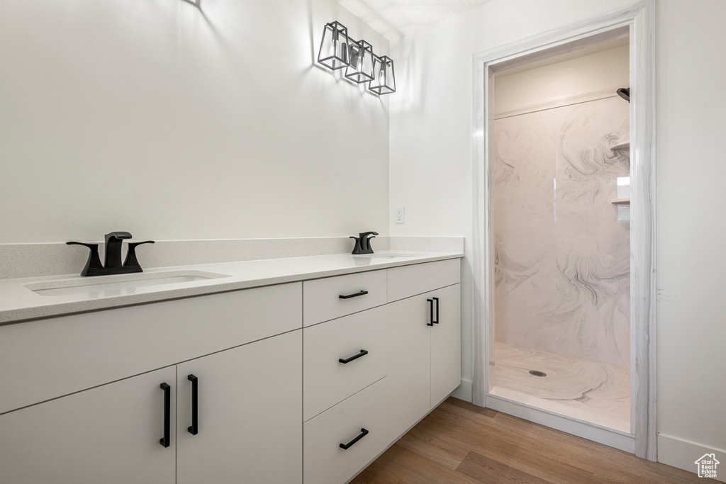 Bathroom with dual vanity, walk in shower, and hardwood / wood-style floors