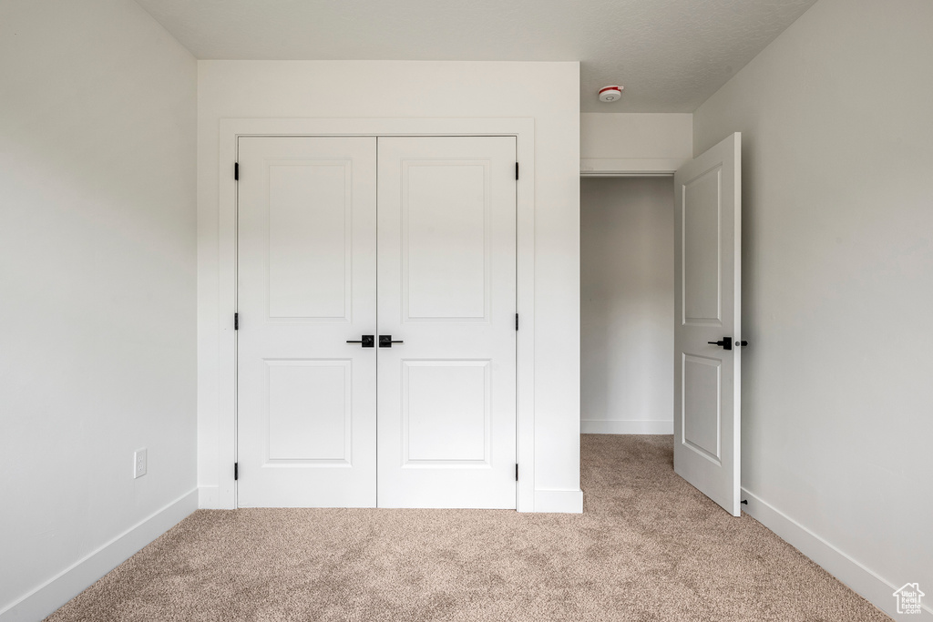 Unfurnished bedroom with a closet and light colored carpet