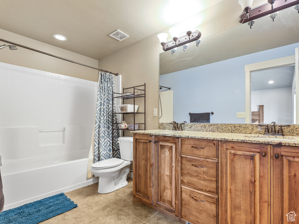 Full bathroom with tile patterned flooring, dual bowl vanity, toilet, and shower / tub combo with curtain