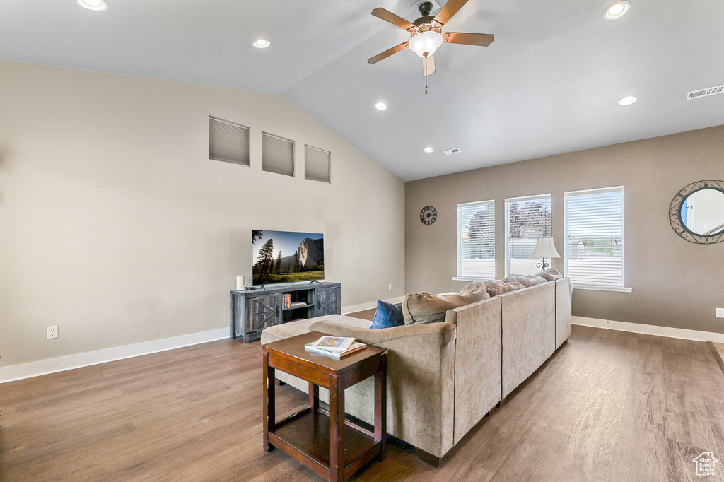 Living room featuring ceiling fan, hardwood / wood-style flooring, and vaulted ceiling